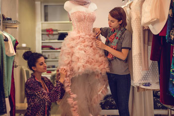 Zwei Modedesignerinnen arbeiten an einem aufwendigen Tüllkleid, das auf einer Modellpuppe sitzt