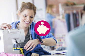 Modedesignerin sitzt an der Nähmaschine. In der Mitte des Bildes ist ein Symbol mit einem Sparschwein und einer Münze platziert.