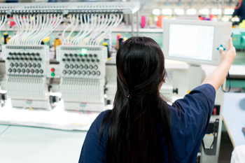 Textiltechnik-Studentin bedient eine Strickmaschine